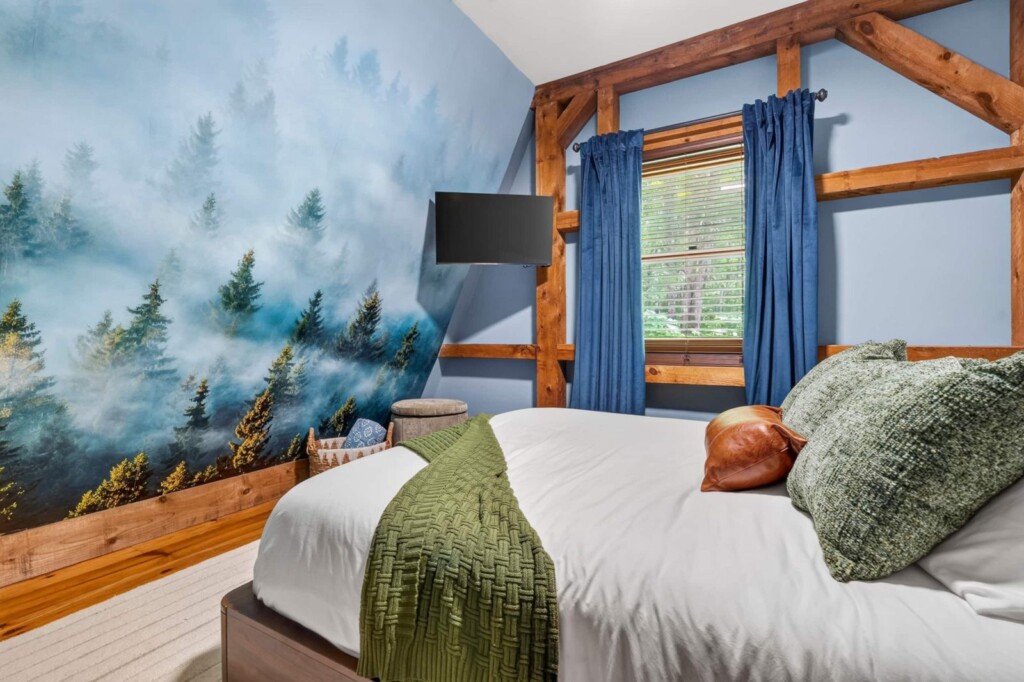 Bedroom with misty forest wall mural and blue curtains at Peak & Pine Retreat