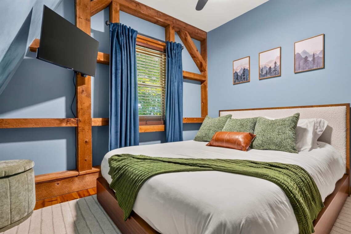 Blue bedroom with timber-frame accents and bed at Peak & Pine Retreat