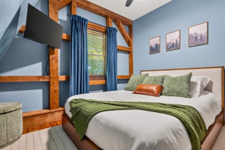 Blue bedroom with timber-frame accents and bed at Peak & Pine Retreat