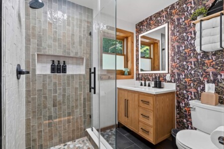 Bathroom with glass walk-in tile shower and mushroom print wallpaper