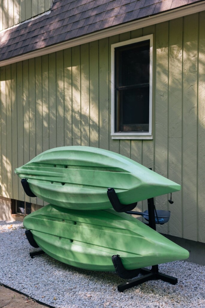 Two green kayaks on a rack beside the house