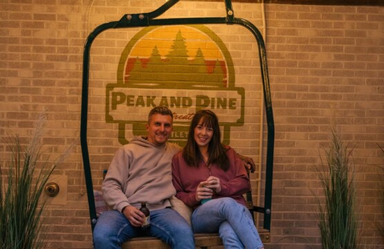 Couple on the chairlift swing under string lights at Peak & Pine Retreat
