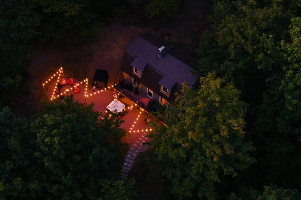 Night drone view of the lit backyard among the trees