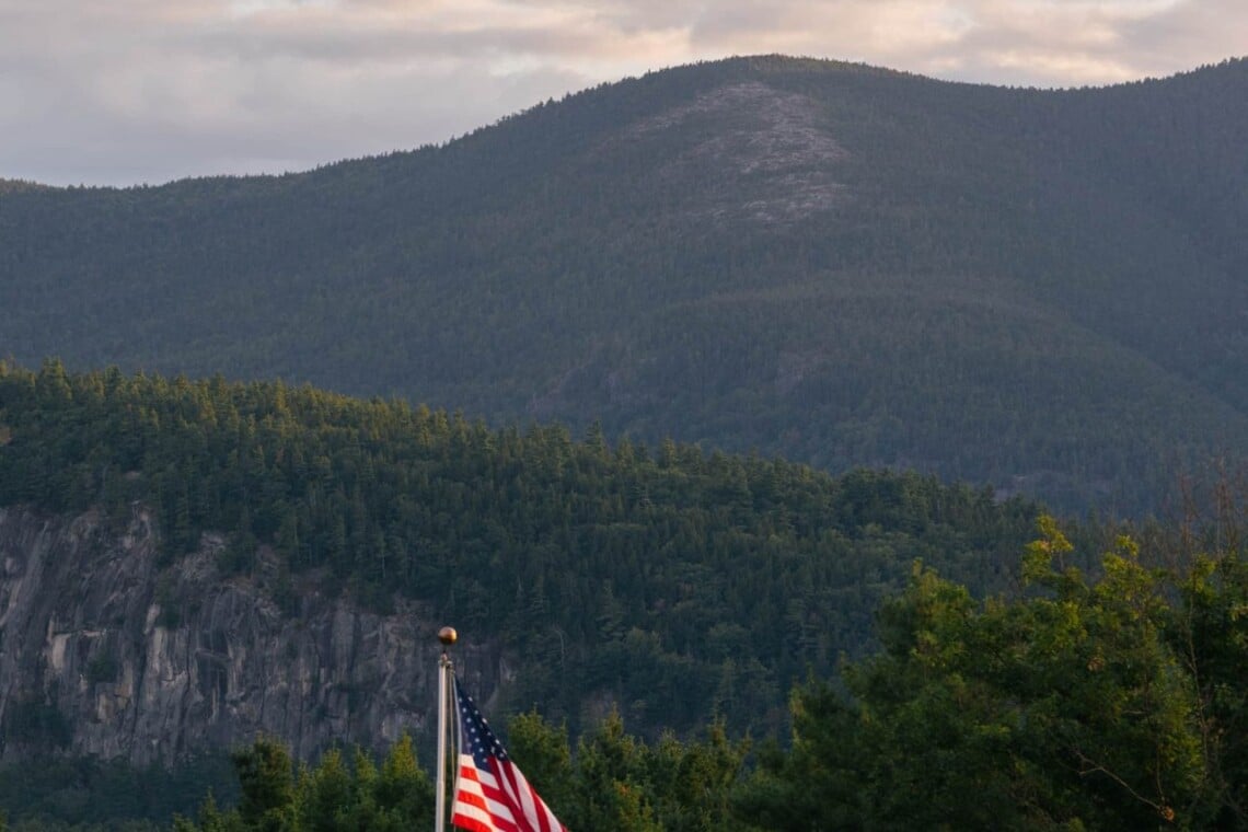 Forested White Mountains peak with American flag in the foreground