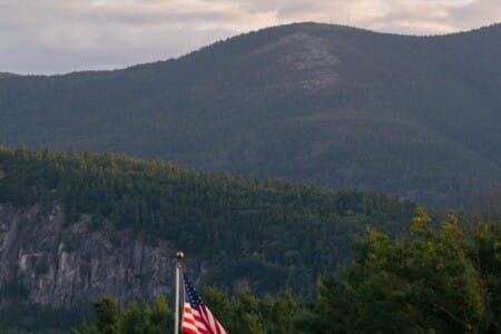Forested White Mountains peak with American flag in the foreground